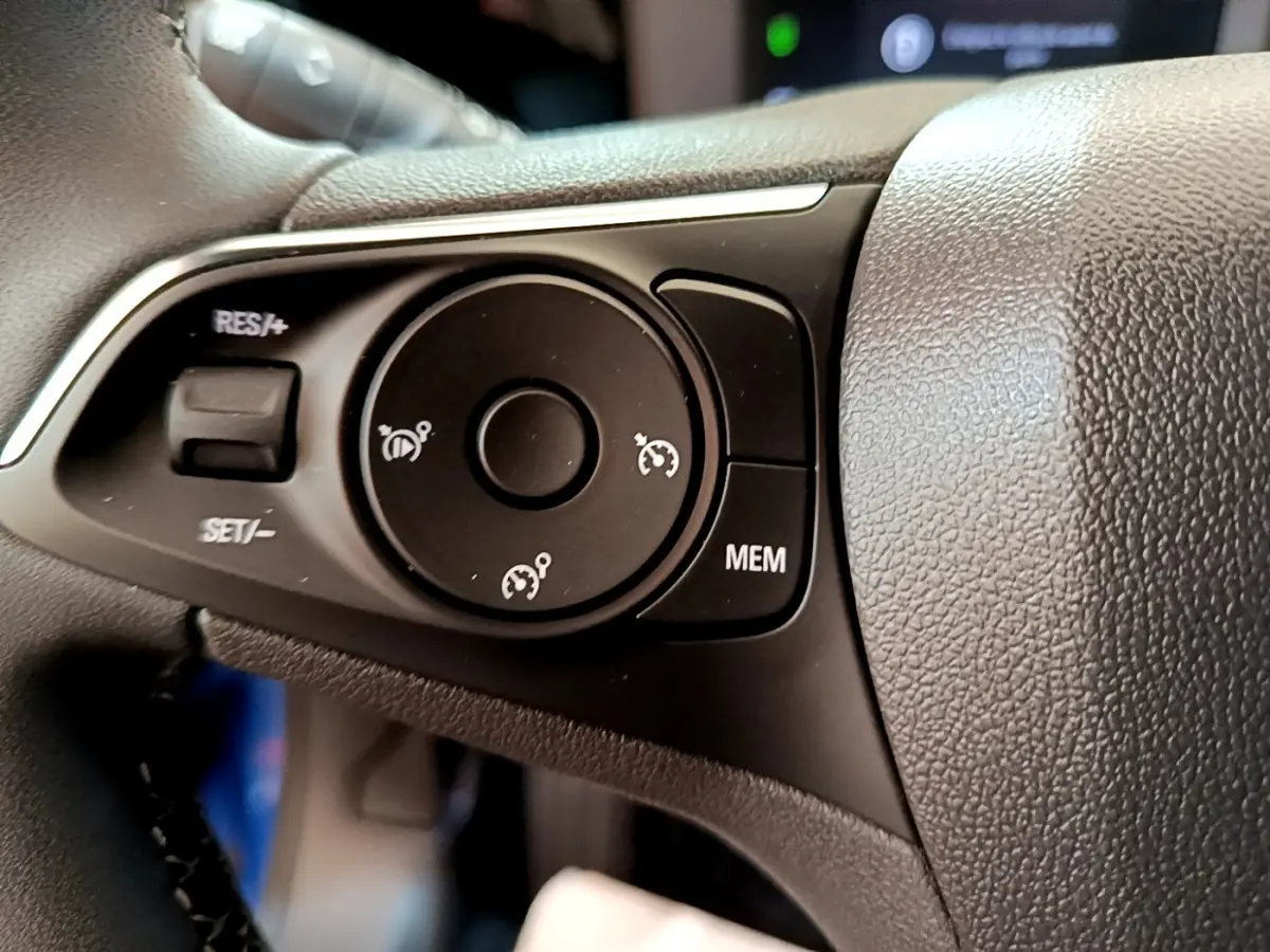Gros plan sur les commandes du régulateur de vitesse au volant cuir de l’Opel Mokka 2024, intérieur noir.