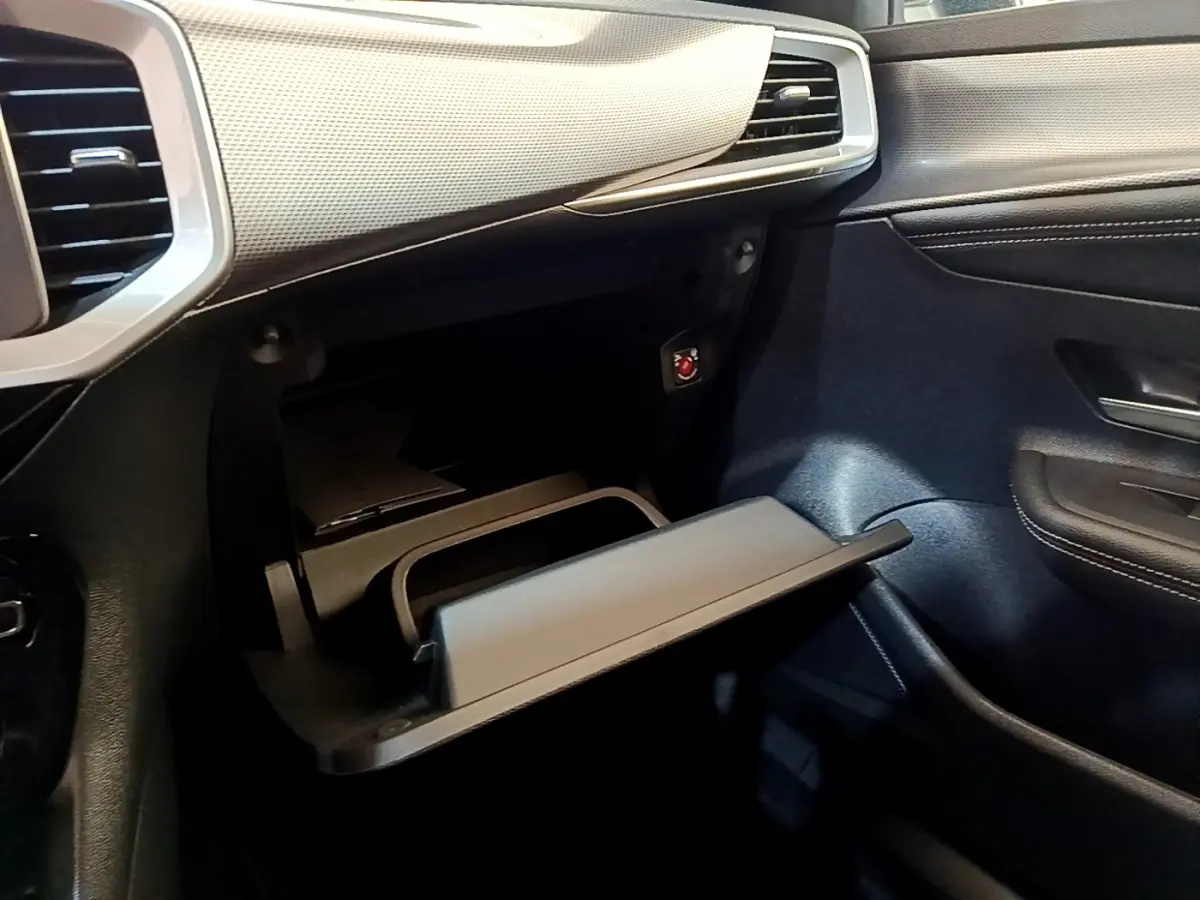 Vue intérieure côté passager de la boîte à gants ouverte du SUV Opel Mokka 2024, avec tableau de bord noir et gris.