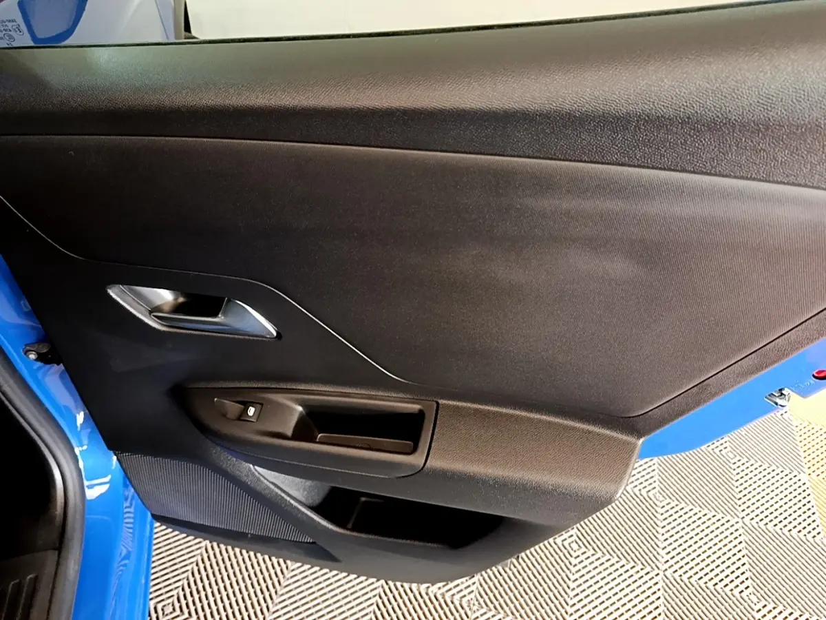 Vue rapprochée de la porte avant gauche bleue de l’Opel Mokka 2024 avec poignée argentée et commande de vitre.