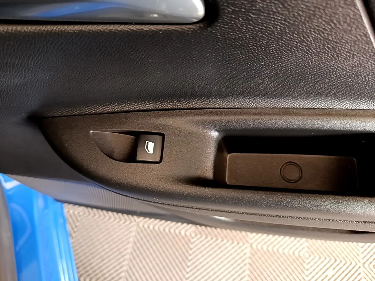 Détail de la commande de lève-vitre sur la porte côté conducteur d’un Opel Mokka bleu 2024.