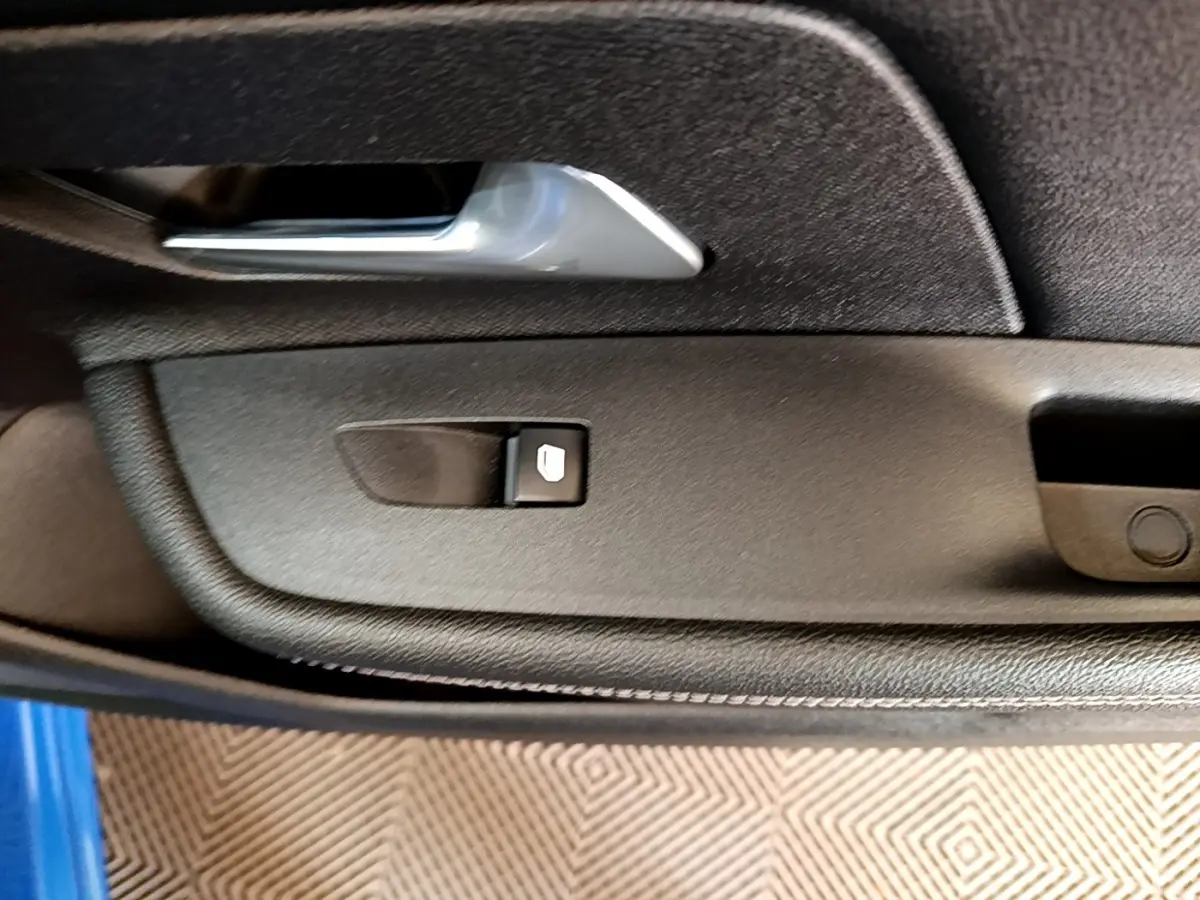 Détail de la commande de lève-vitre sur la porte côté conducteur d’un Opel Mokka bleu 2024.