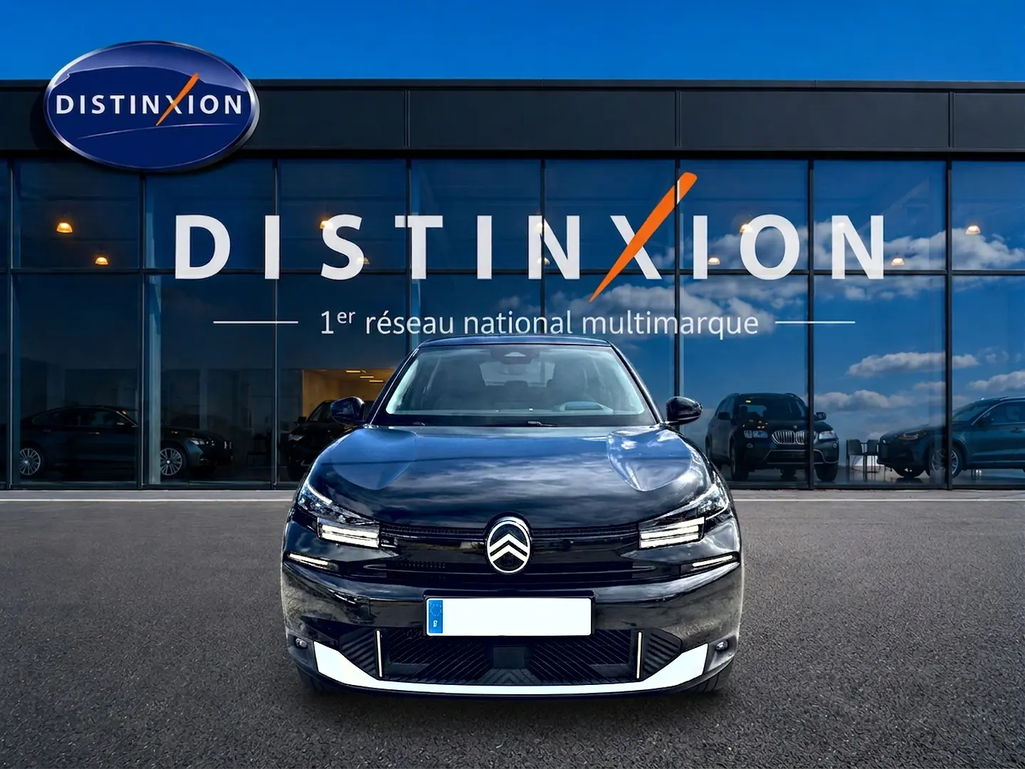 Vue avant d'une Citroën C4 X noire 2025, avec calandre distinctive et phares LED, devant une vitrine Distinxion.