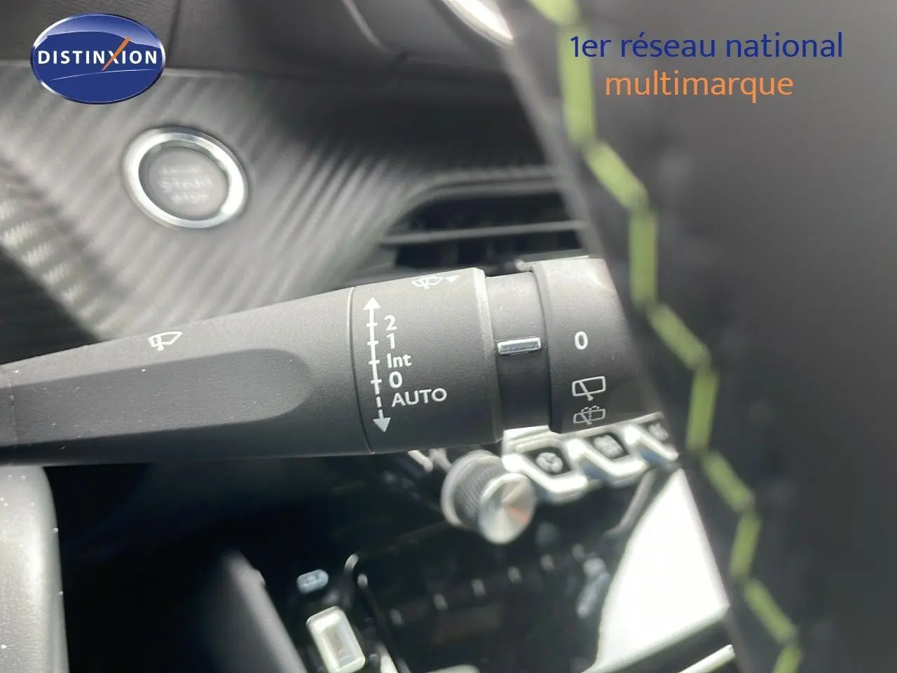 Gros plan sur la commande d'essuie-glace de la Peugeot 208 GT 2025 avec intérieur noir et surpiqûres vertes.