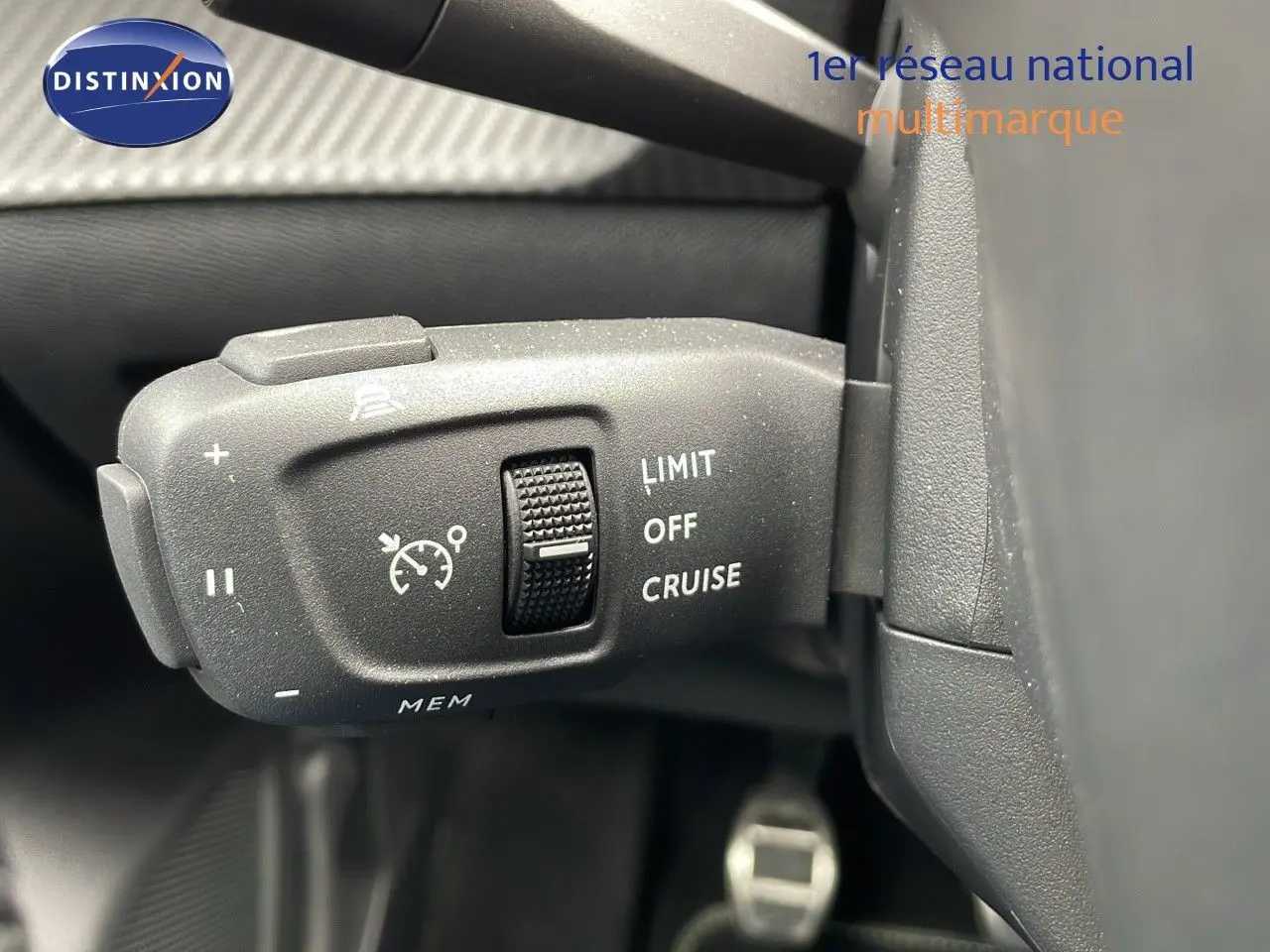 Gros plan sur la commande de régulateur de vitesse du Peugeot 208 gris sélénium avec toit noir, intérieur sombre.