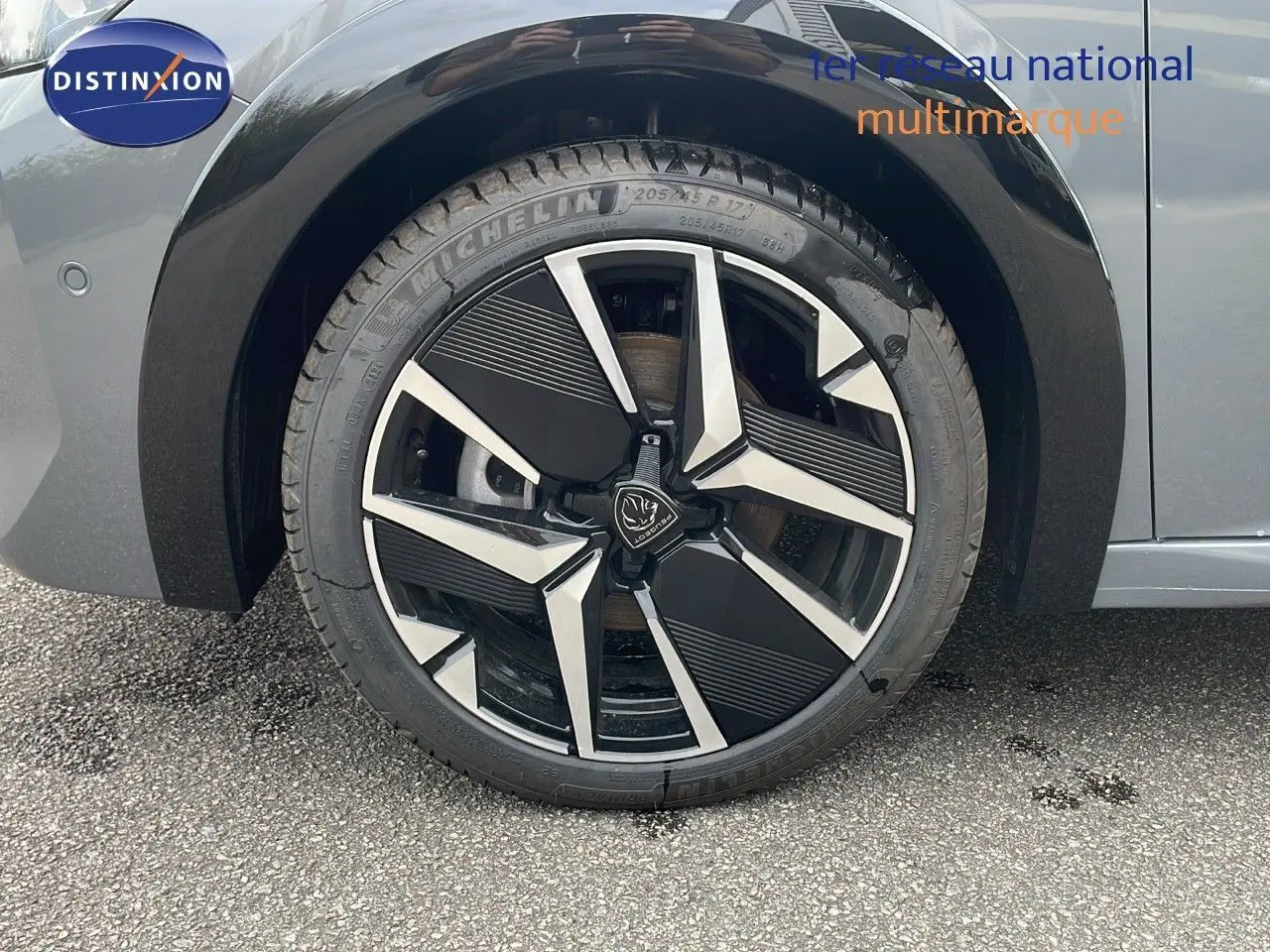 Gros plan sur la roue avant gauche de la Peugeot 208 gris selenium avec jante alliage bicolore moderne.