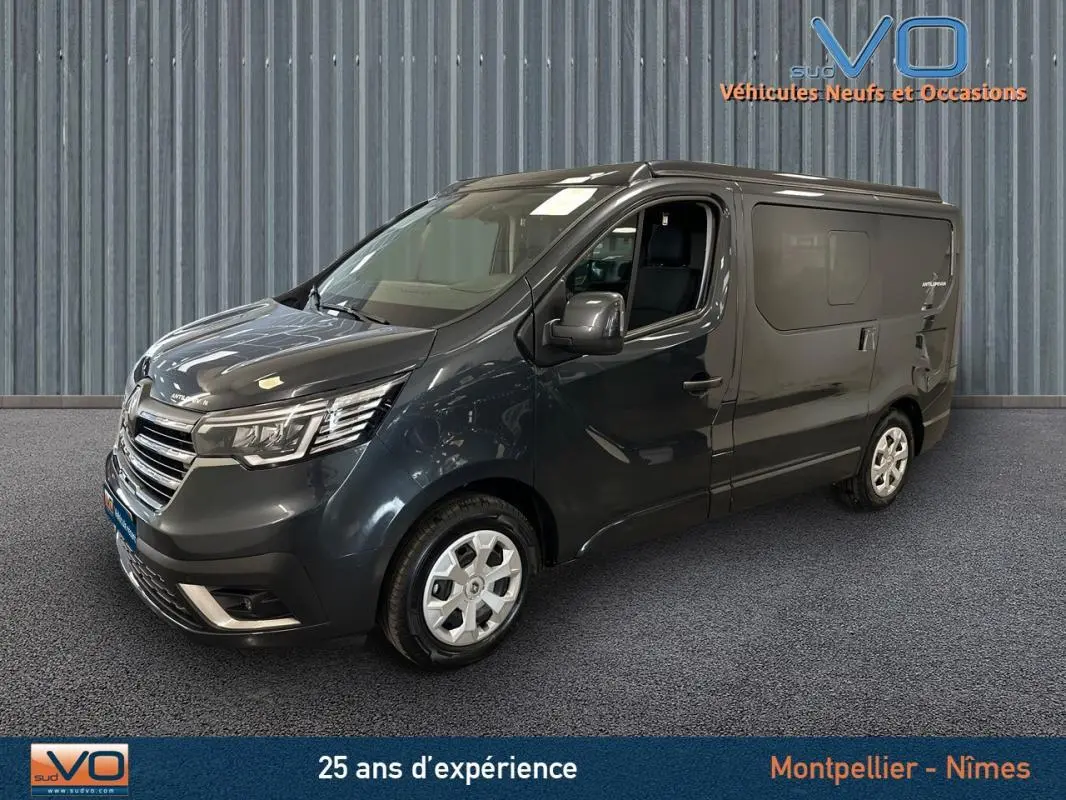 Renault Trafic Fourgon gris en 3/4 avant droit, avec vitres surteintées et jantes argentées visibles en intérieur showroom.