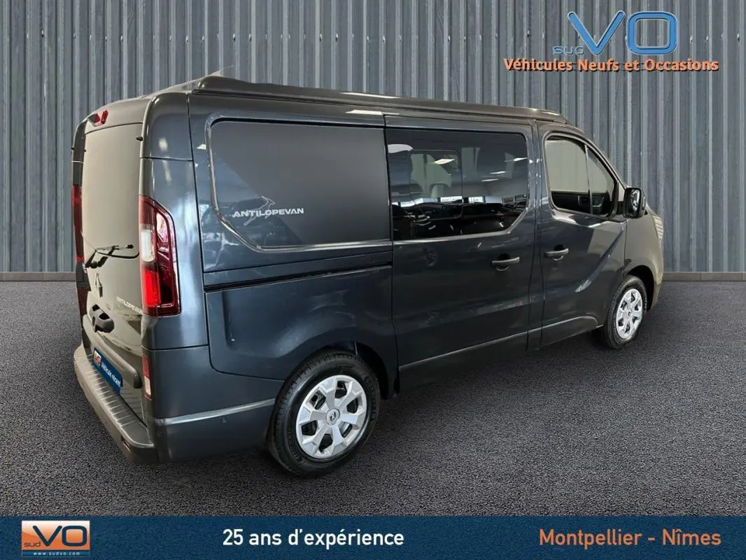 Renault Trafic Fourgon gris en 3/4 arrière droit, vitres surteintées et logo Antilopevan visible sur la porte latérale.