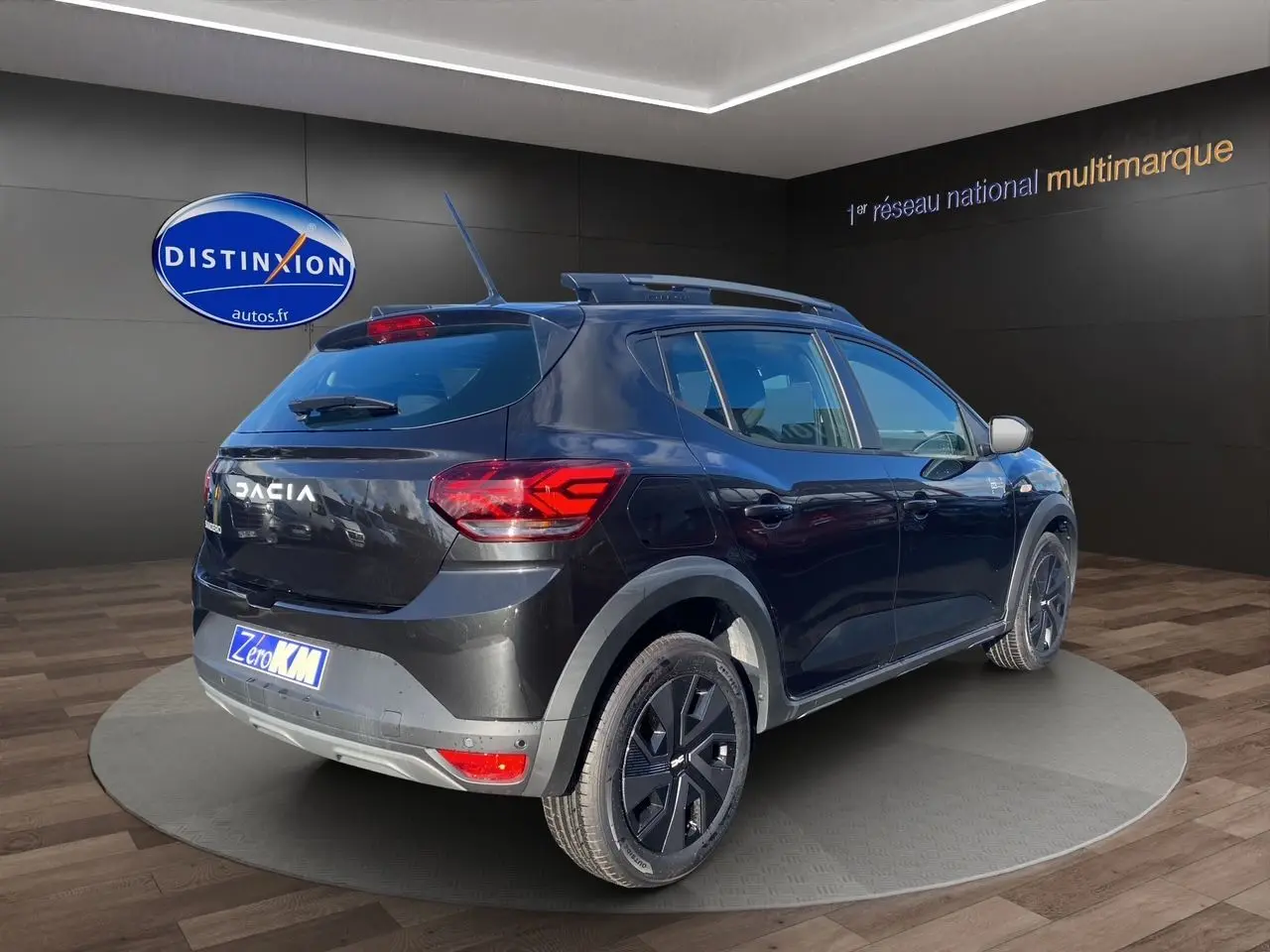 Vue 3/4 arrière droite d'une Dacia Sandero Stepway noire avec barres de toit et feux LED distinctifs.
