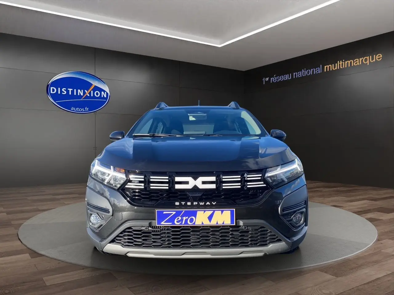 Vue frontale d'une Dacia Sandero Stepway noire avec calandre distinctive et feux LED allumés en showroom.