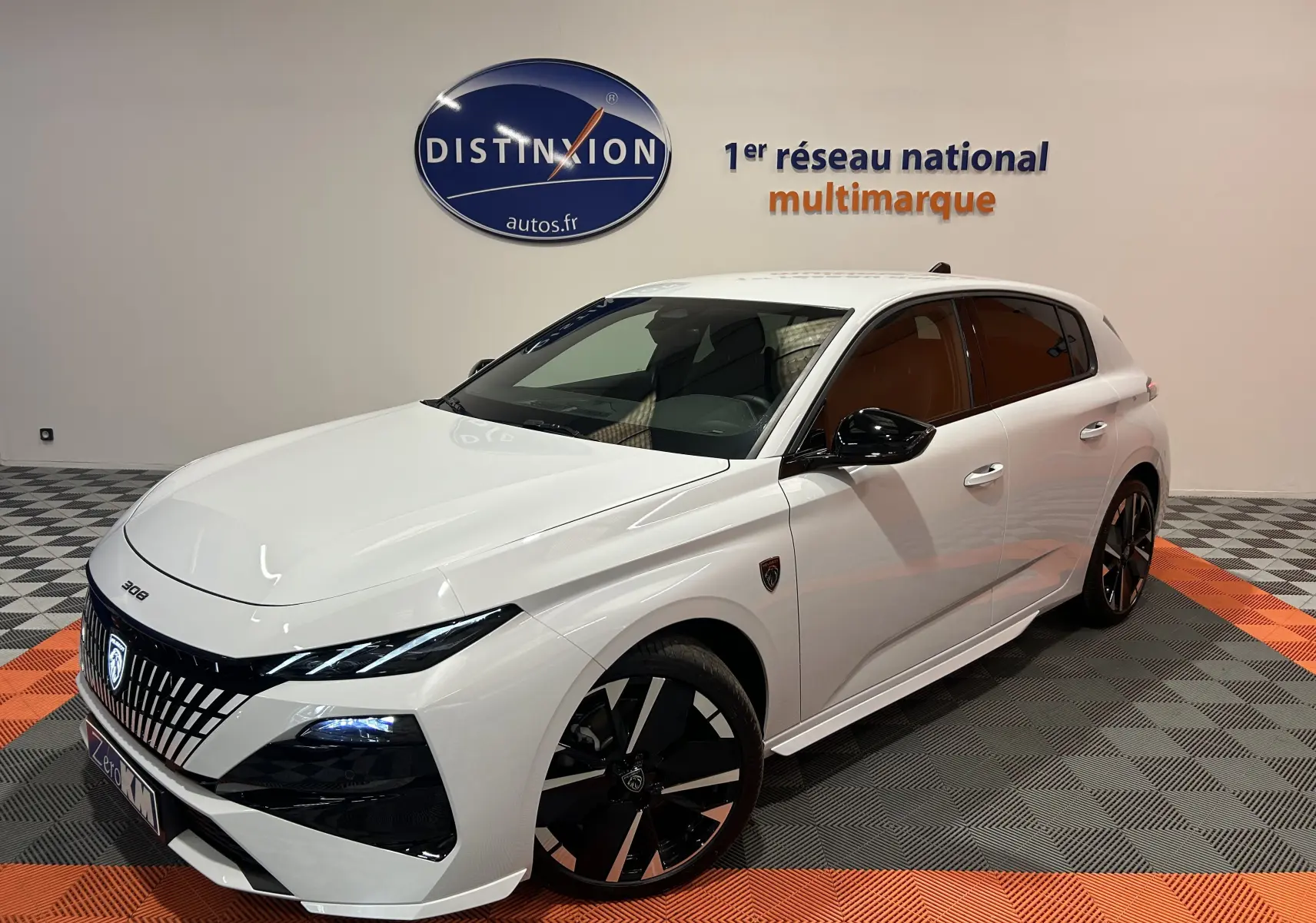 Peugeot 308 III Ph.2 Hybrid blanc Okenite vue 3/4 avant droit en intérieur avec jantes noires distinctives.