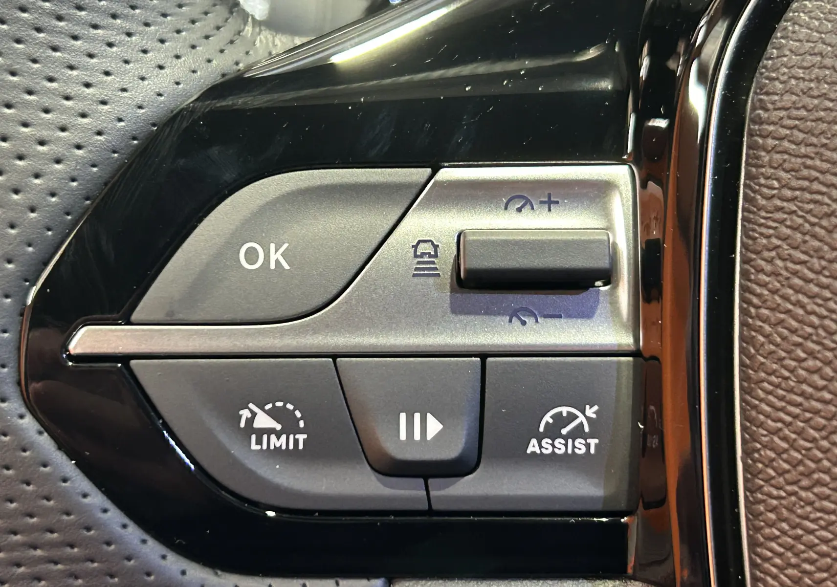 Gros plan sur les commandes de régulateur de vitesse et assistance au volant d’une Peugeot 308 blanc Okenite.