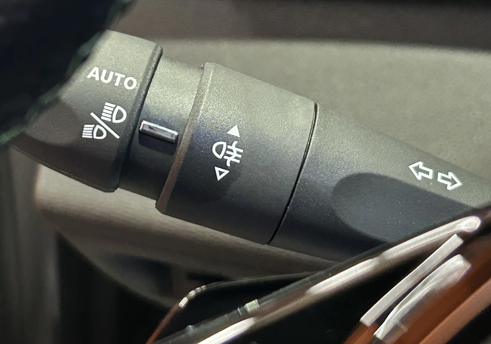 Gros plan sur la commande des feux et clignotants dans l’habitacle d’une Peugeot 308 blanc Okenite, version hybride.