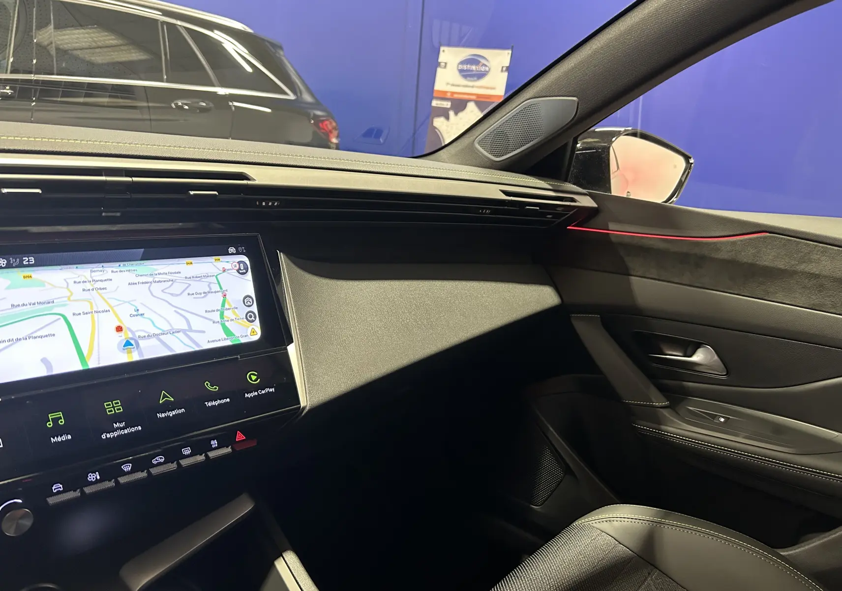 Vue intérieure côté passager de la Peugeot 308 blanche, mettant en valeur l'écran tactile GPS et les finitions modernes.