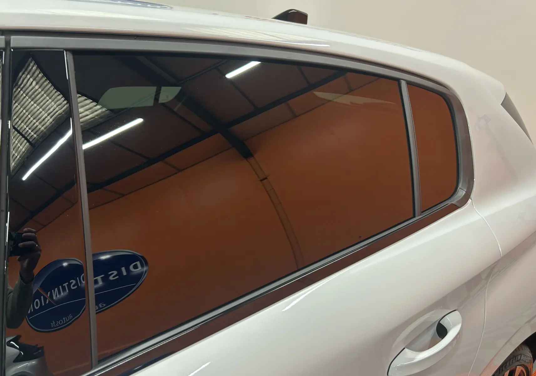 Vue latérale gauche sur la porte arrière blanche Okenite de la Peugeot 308 III Ph.2 HYBRID 145 GT avec vitre teintée.