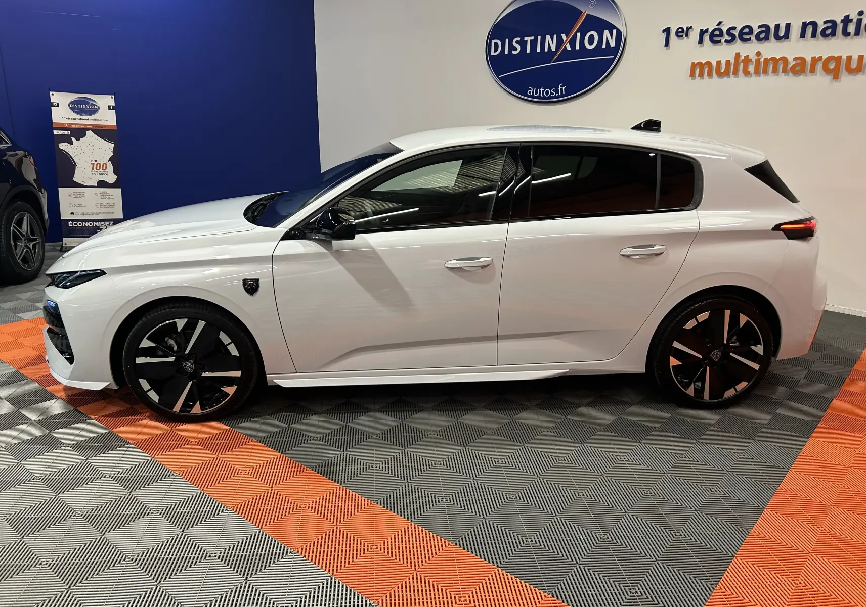 Vue latérale droite d'une Peugeot 308 III Ph.2 HYBRID 145 GT blanche Okenite avec jantes noires et vitres teintées.