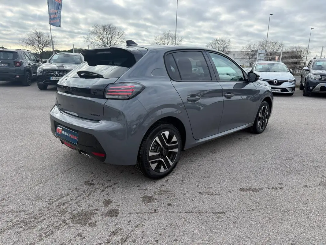 Vue 3/4 arrière droite d'une Peugeot 208 Hybrid 145 gris avec jantes alliage et antenne requin, stationnée en extérieur.