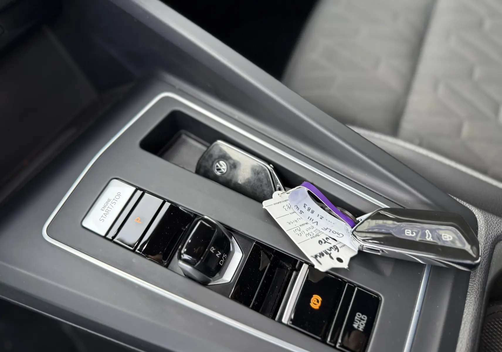 Gros plan sur la console centrale d’une Volkswagen Golf SW gris lunaire, avec clé et levier de boîte automatique DSG7.