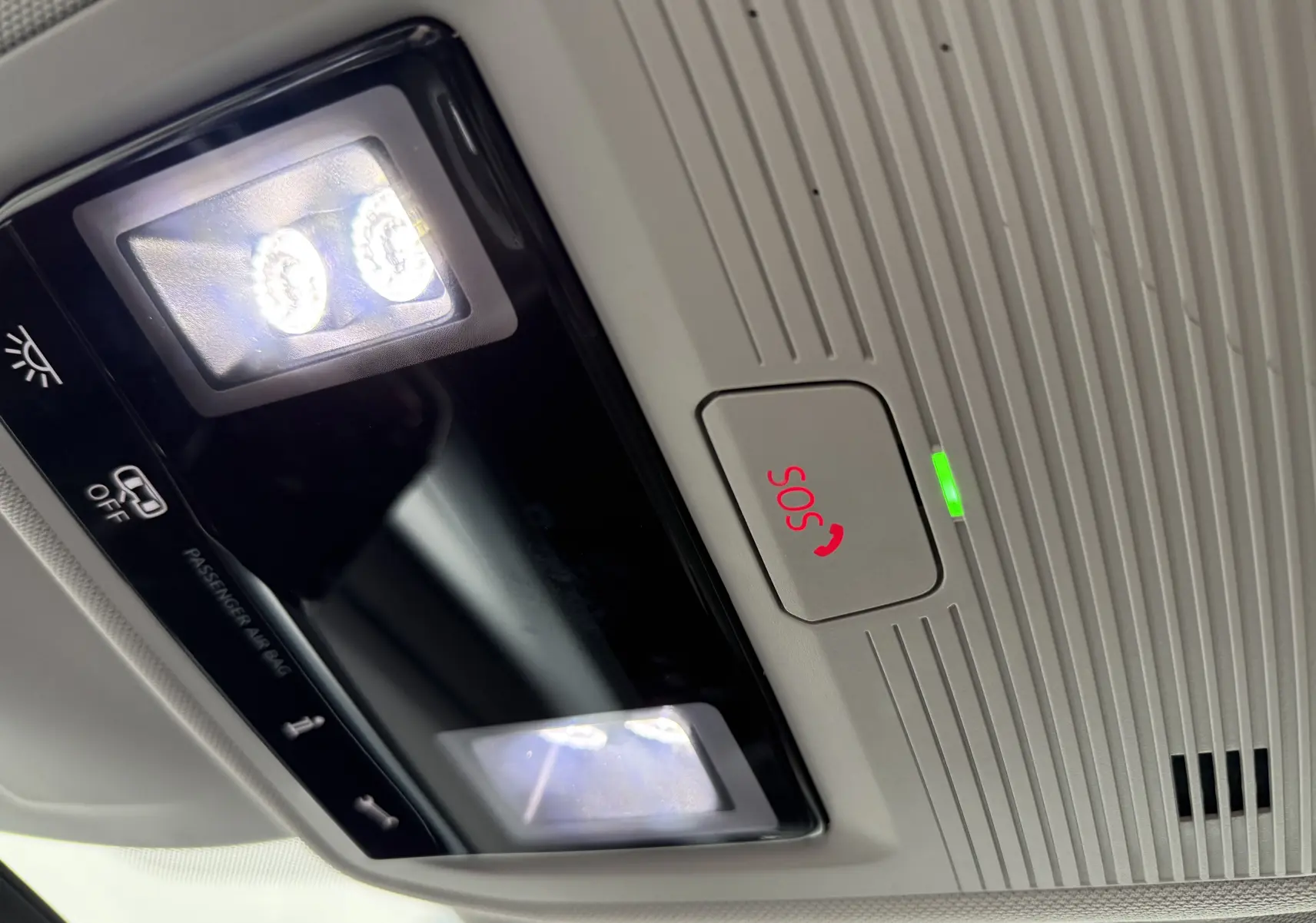 Gros plan sur le plafonnier intérieur gris clair de la Volkswagen Golf SW avec éclairage LED et bouton SOS rouge allumé.