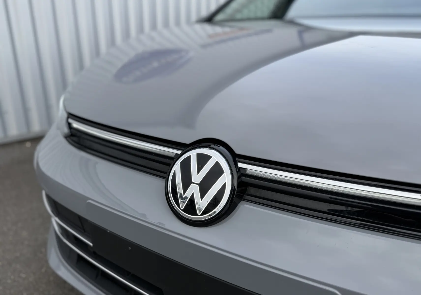Gros plan sur la calandre avant gris lunaire d'une Volkswagen Golf SW 2.0 TDI 150 GOAL DSG7 avec logo VW central.
