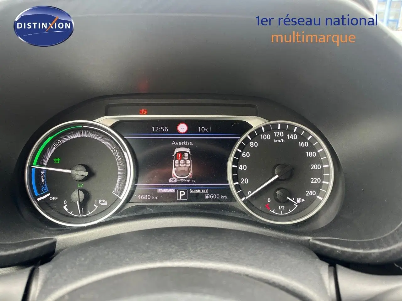 Tableau de bord du Nissan Juke blanc nacré 2024 montrant compteur vitesse, jauge essence et écran digital d'alerte.