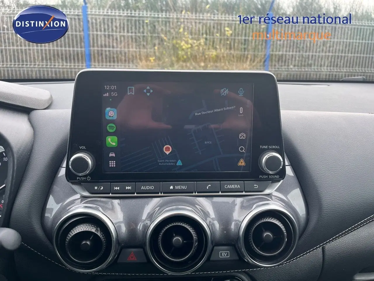 Vue rapprochée de la console centrale du Nissan Juke 2024, écran tactile affichant la navigation et aérateurs ronds chromés.