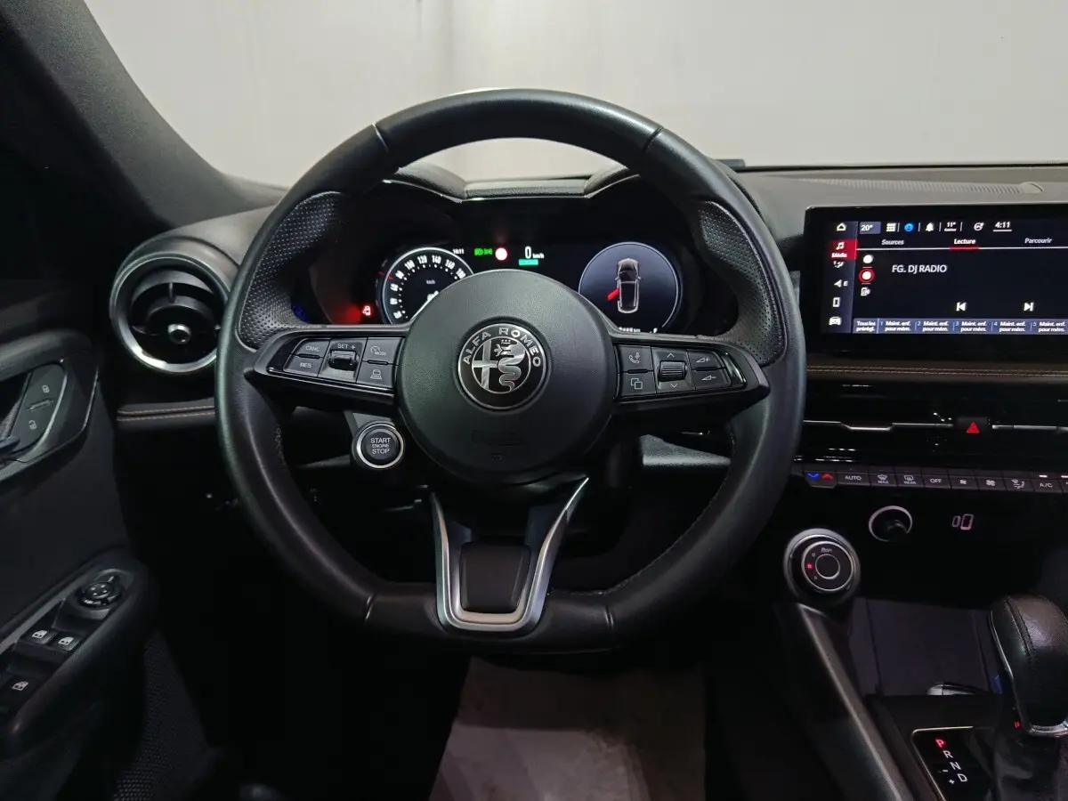 Vue frontale du volant cuir noir de l'Alfa Romeo Tonale 2023 avec tableau de bord digital et écran tactile central.