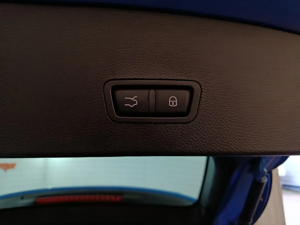 Gros plan sur les boutons d'ouverture et de verrouillage du coffre du hayon d'une Alfa Romeo Tonale bleu.