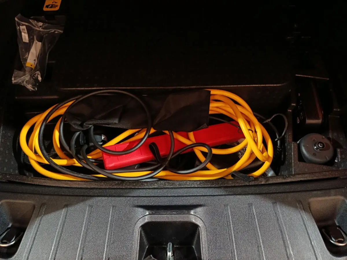 Coffre ouvert d'Alfa Romeo Tonale bleu 2023 montrant câble de recharge hybride rechargeable jaune et noir rangé.