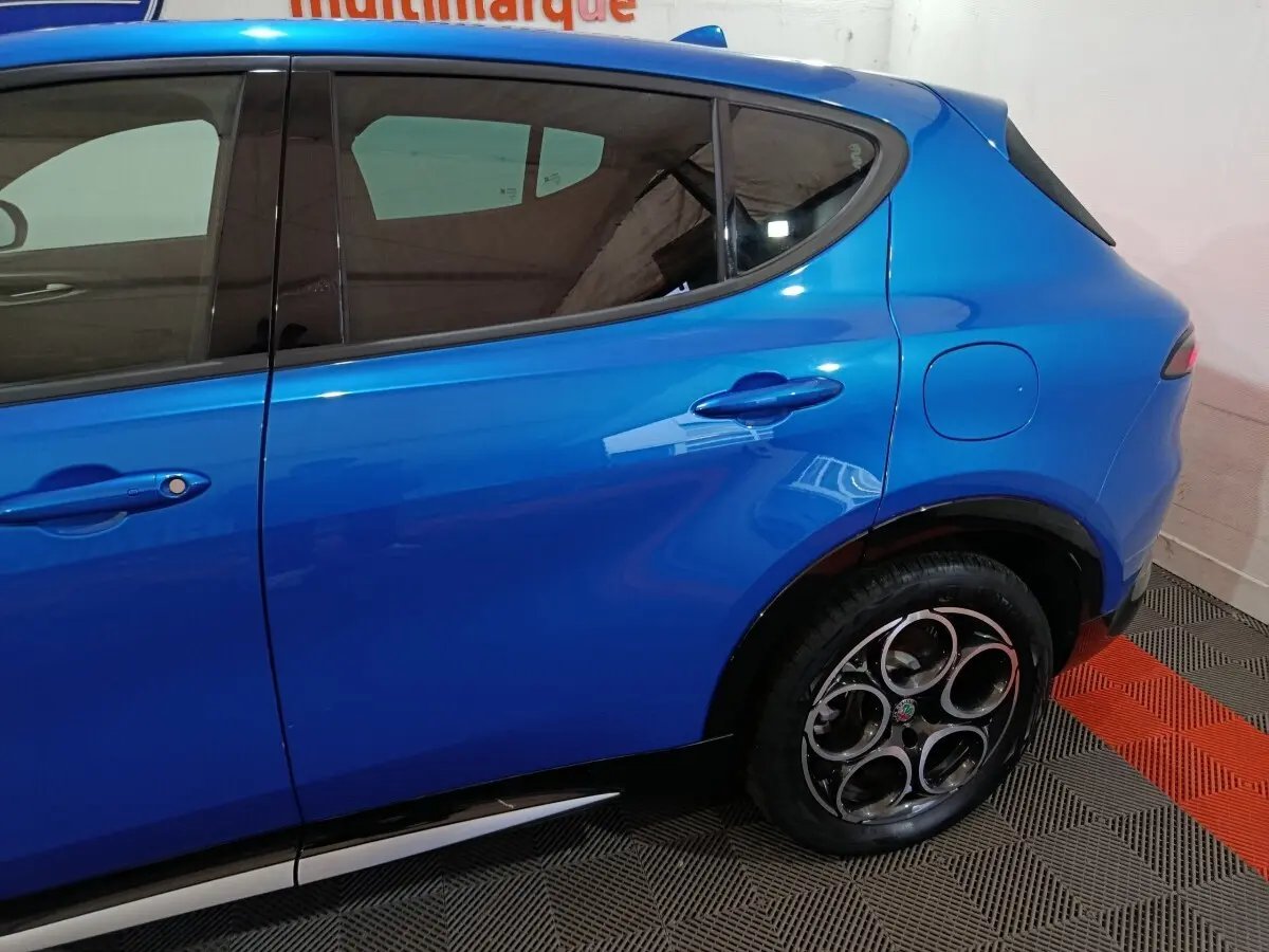 Vue latérale droite sur l'arrière d'un Alfa Romeo Tonale bleu avec poignées de porte et trappe à carburant visibles.
