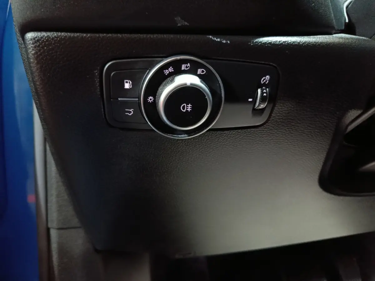 Gros plan sur le bouton de commande des feux sur tableau de bord noir de l'Alfa Romeo Tonale bleu.