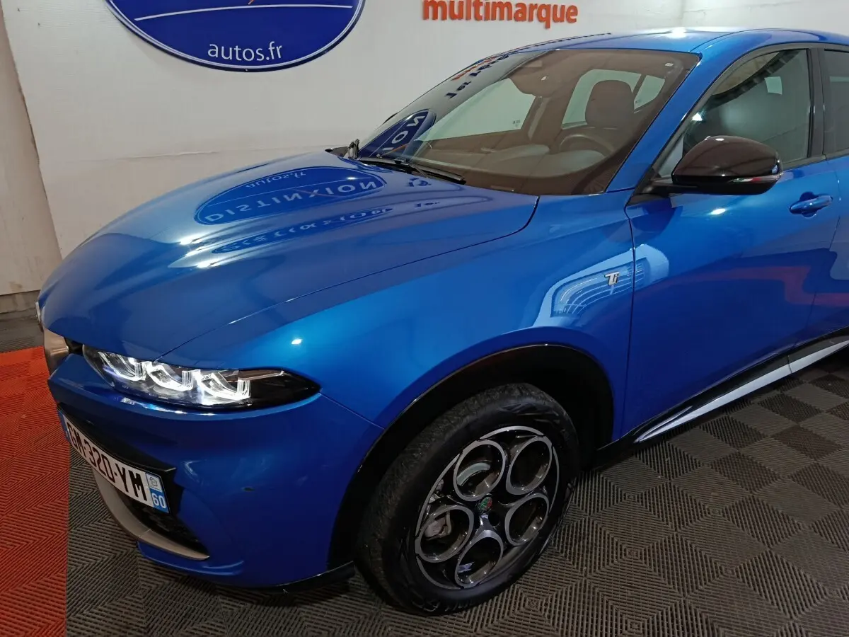Vue 3/4 avant droit d'une Alfa Romeo Tonale bleu électrique avec jantes spécifiques et badge Ti sur l'aile.