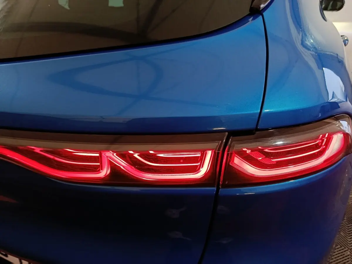 Gros plan sur le feu arrière droit rouge vif d'une Alfa Romeo Tonale hybride rechargeable bleu métallisé.