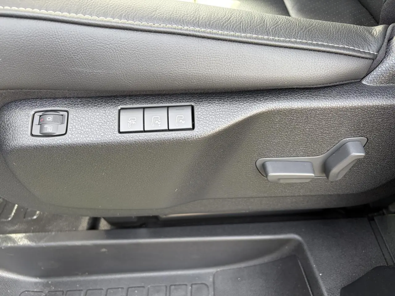 Détail des commandes de réglage électrique du siège conducteur en cuir noir du Citroën Jumpy gris acier.