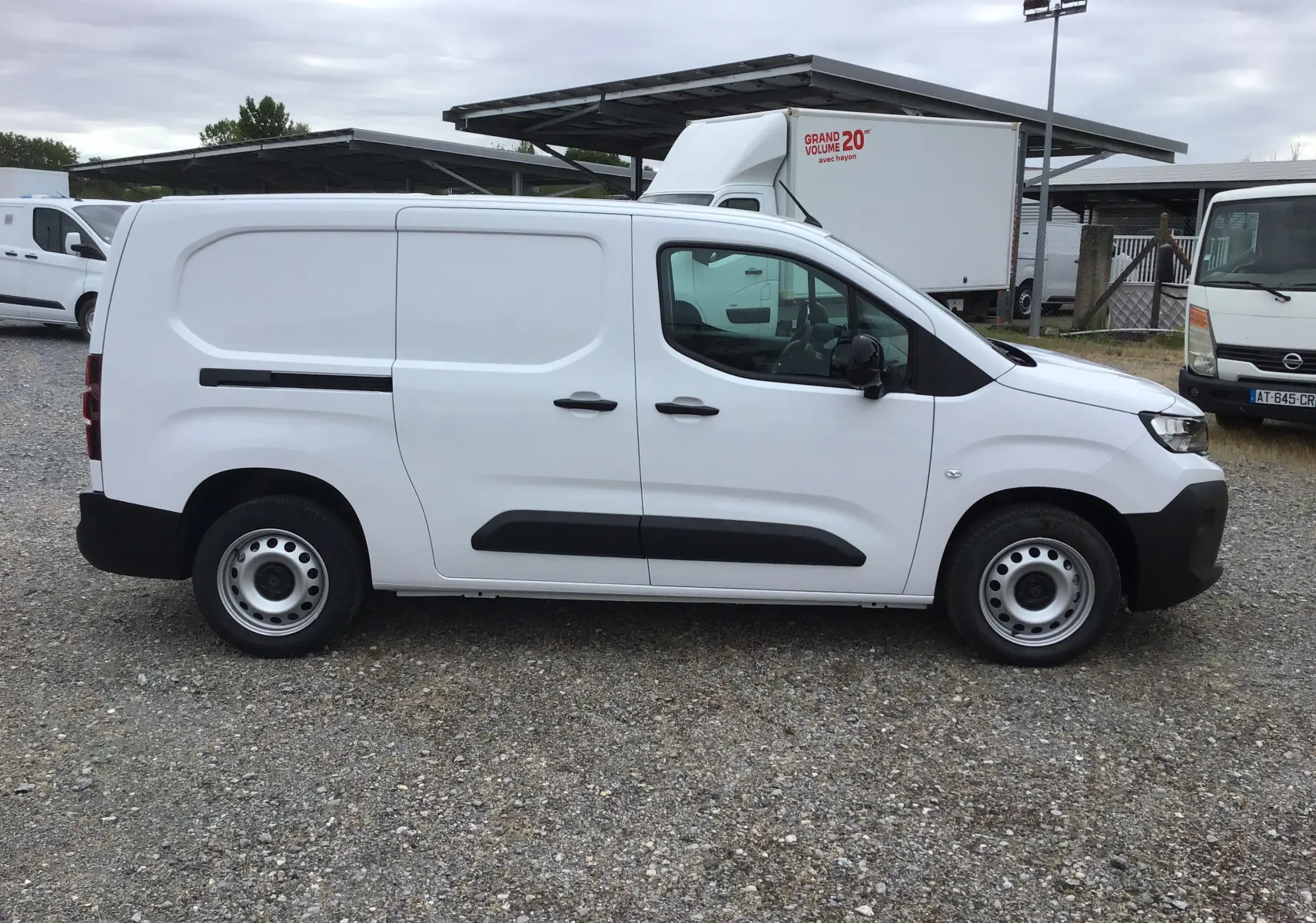 Vue de profil côté gauche d’un utilitaire blanc Peugeot Partner XL 2026 avec porte latérale coulissante et jantes acier.