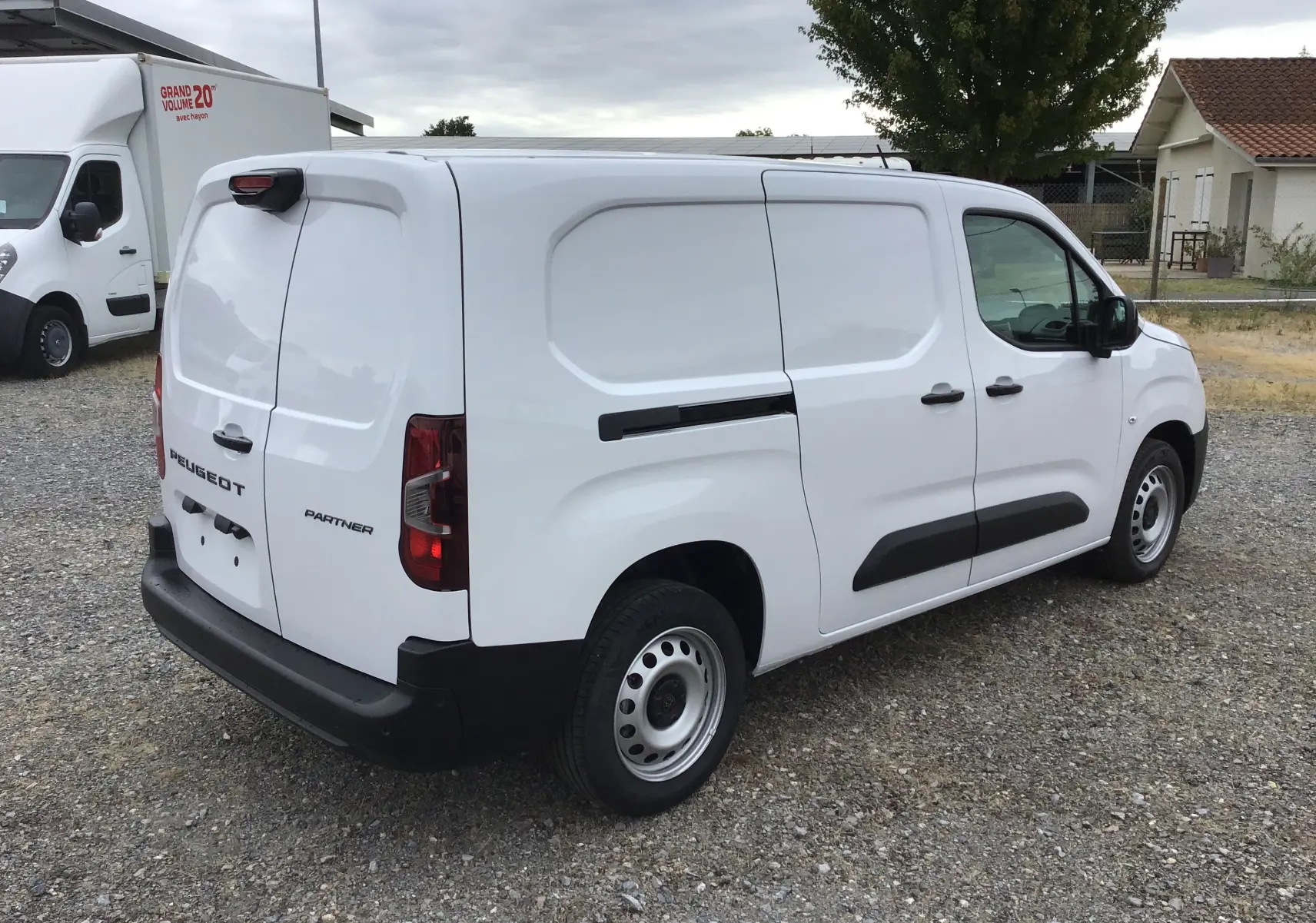 Vue 3/4 arrière droite d’un utilitaire Peugeot Partner blanc, avec portes arrière battantes et protections latérales noires.