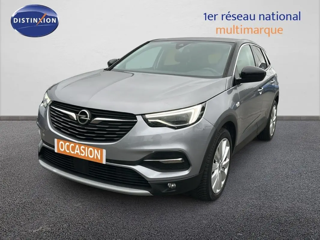 Opel Grandland X gris clair vu en 3/4 avant droit avec jantes alliage 19 pouces et phares LED allumés.