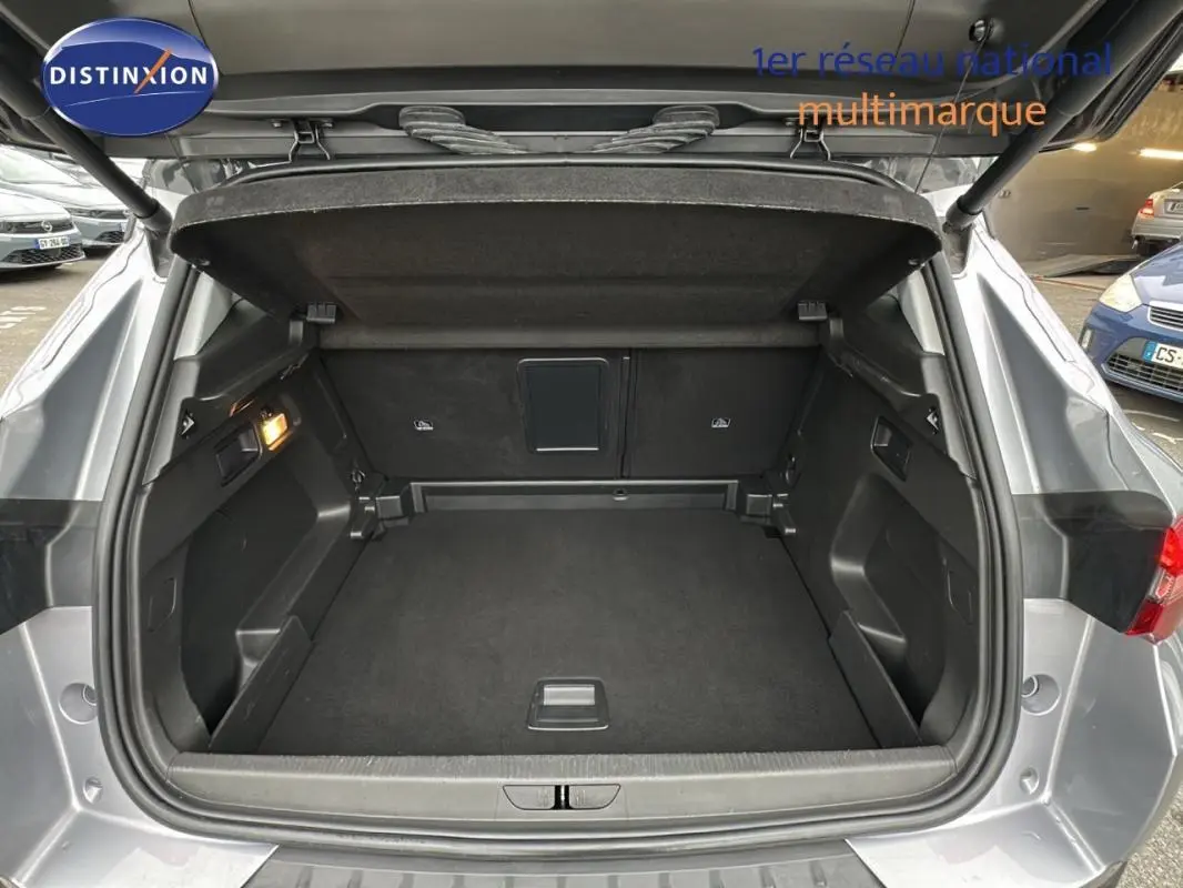 Coffre ouvert vu de l'arrière d'un Opel Grandland X gris clair, montrant un espace de chargement propre et spacieux.