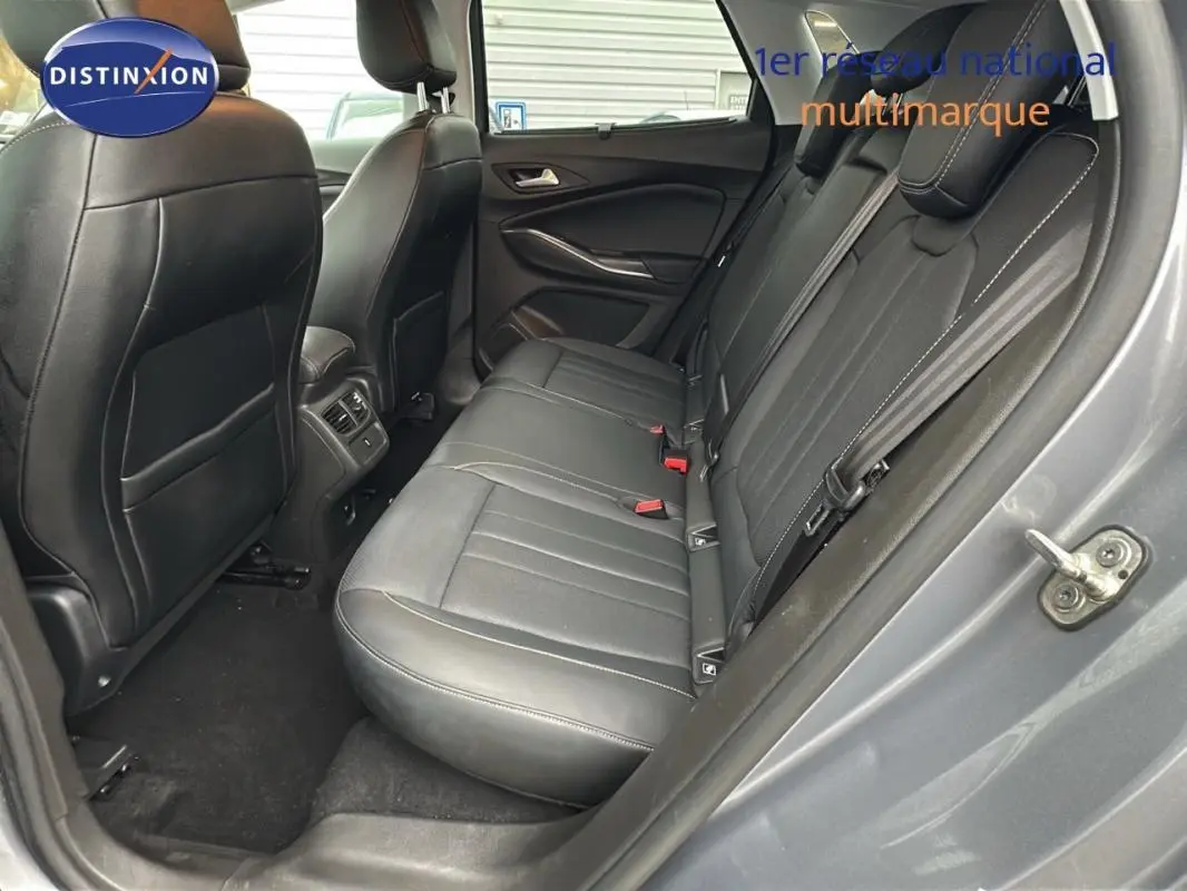 Vue côté droit de l'habitacle arrière d'un Opel Grandland X gris clair avec sièges en cuir noir et coutures blanches.