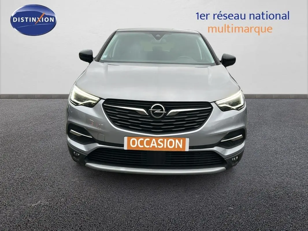 Vue frontale d'un Opel Grandland X gris clair avec phares LED allumés et plaque "OCCASION" visible.