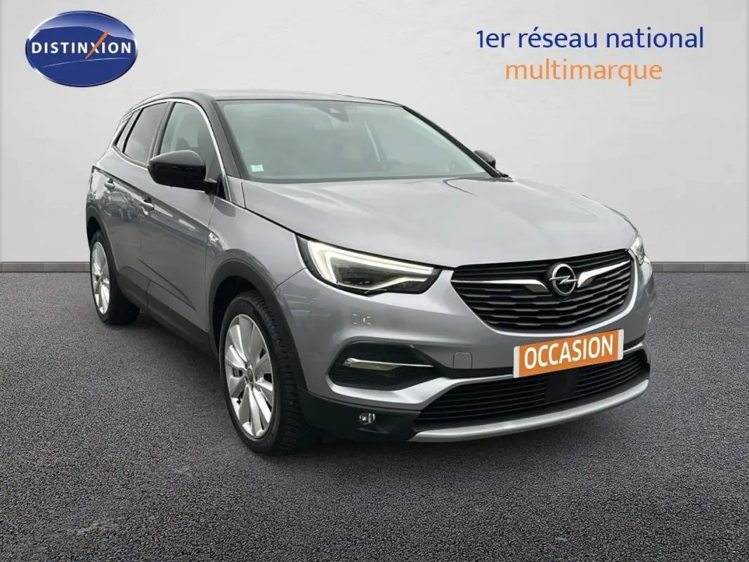 Opel Grandland X gris clair vu en 3/4 avant droit, avec phares LED et jantes alliage 19 pouces visibles.