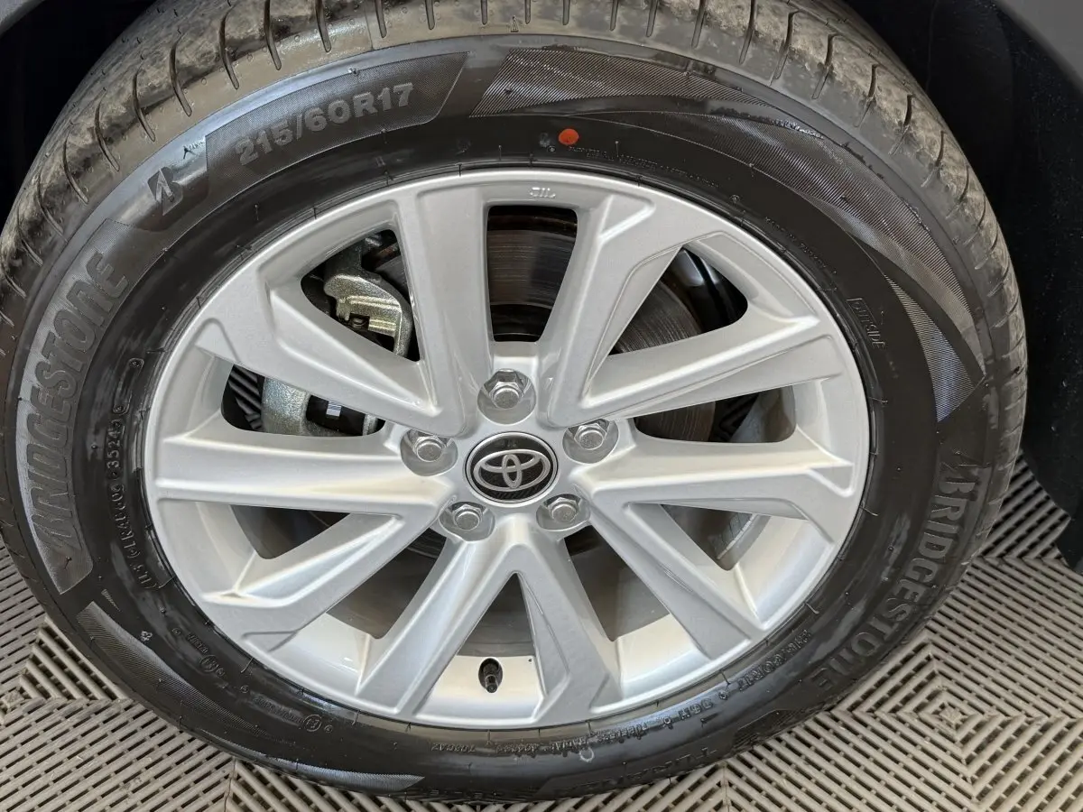 Gros plan sur la jante argentée avec logo Toyota d’un Toyota C-HR blanc, pneu Bridgestone visible.