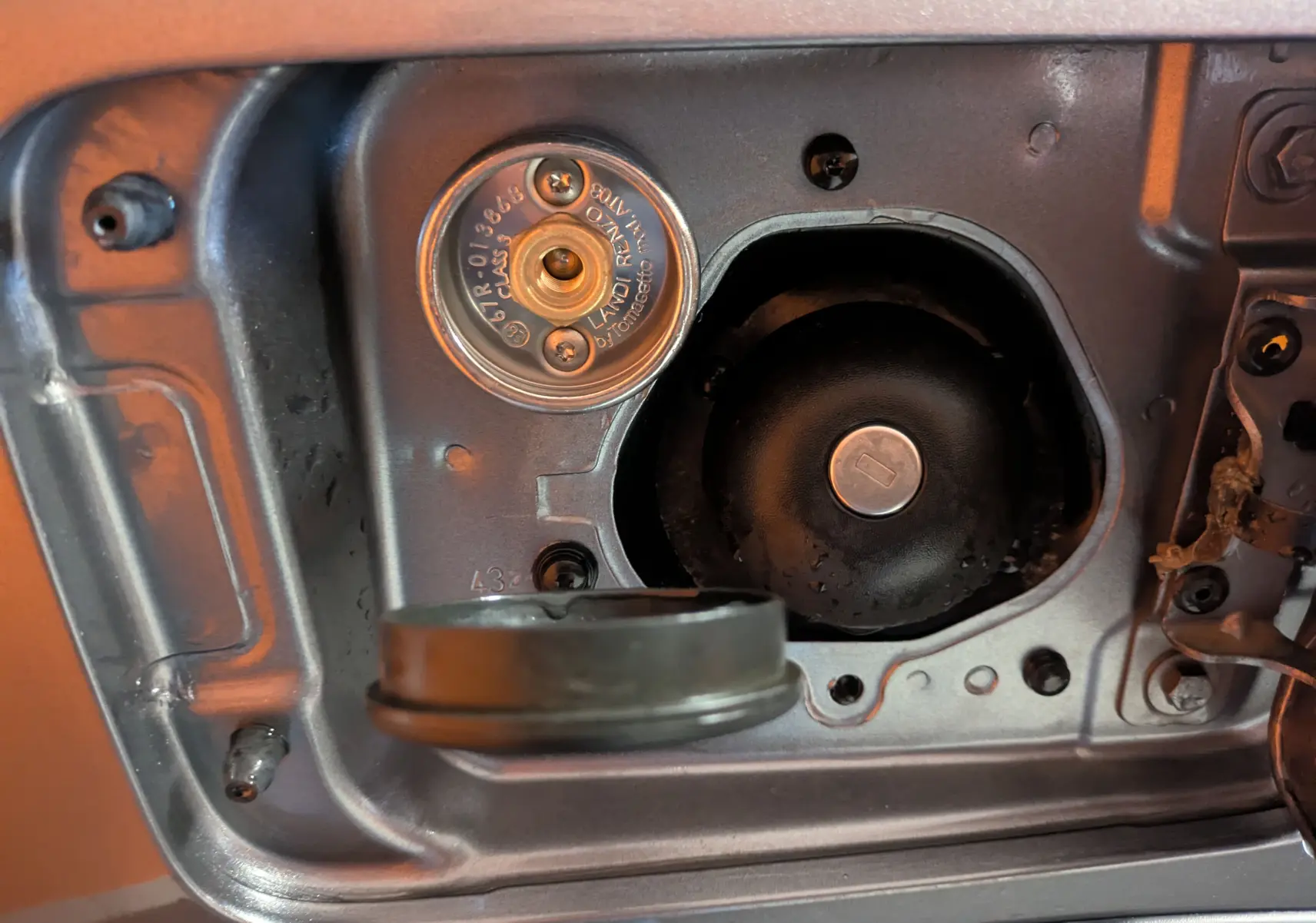 Gros plan sur la trappe de remplissage GPL du Dacia Jogger gris schiste métal, montrant le bouchon ouvert et l’adaptateur.