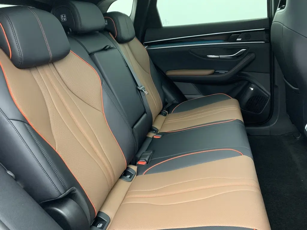 Gros plan sur le volant et le tableau de bord numérique du BYD SEAL U 2025, intérieur noir avec surpiqûres rouges.