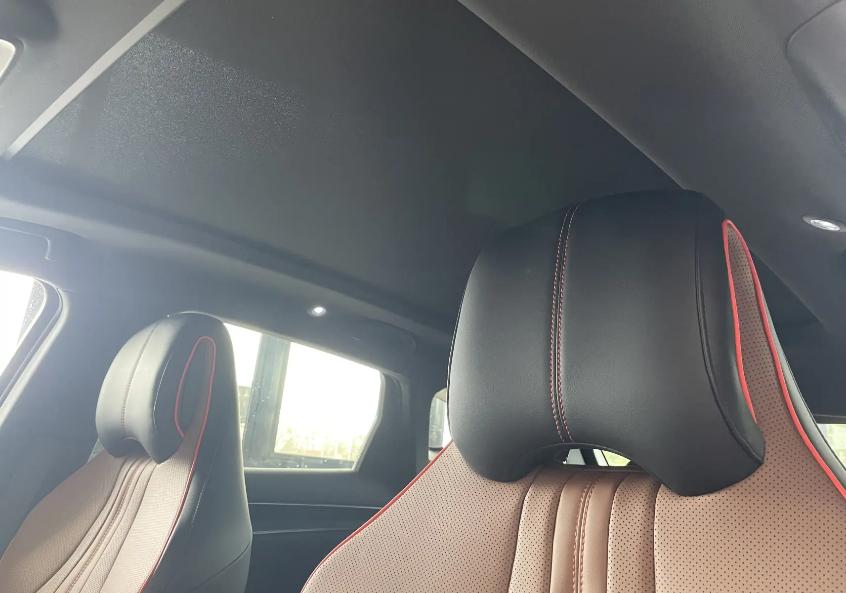 Gros plan sur les sièges avant en similicuir noir et marron avec surpiqûres rouges du BYD SEAL U 2025.