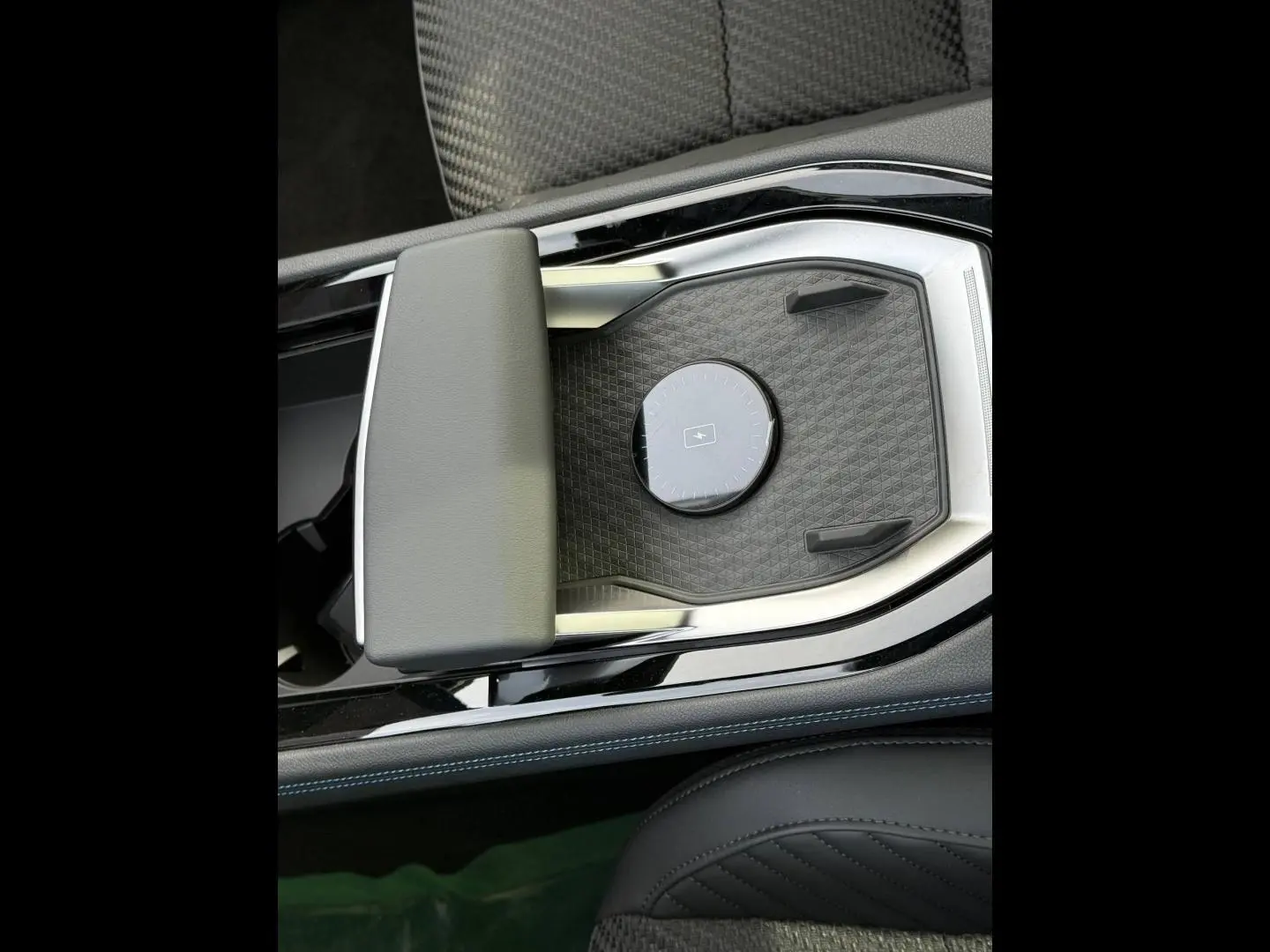 Vue rapprochée de la console centrale noire avec accoudoir gris et surface de recharge sans fil du Renault Austral 2026.