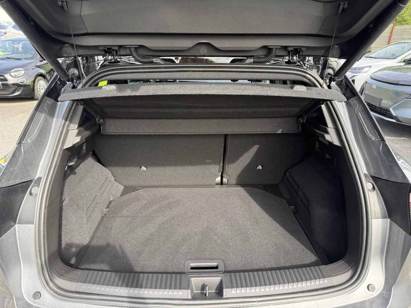 Coffre ouvert vu de l'arrière d'un Renault Austral gris Schiste satin avec cache-bagages et intérieur noir.
