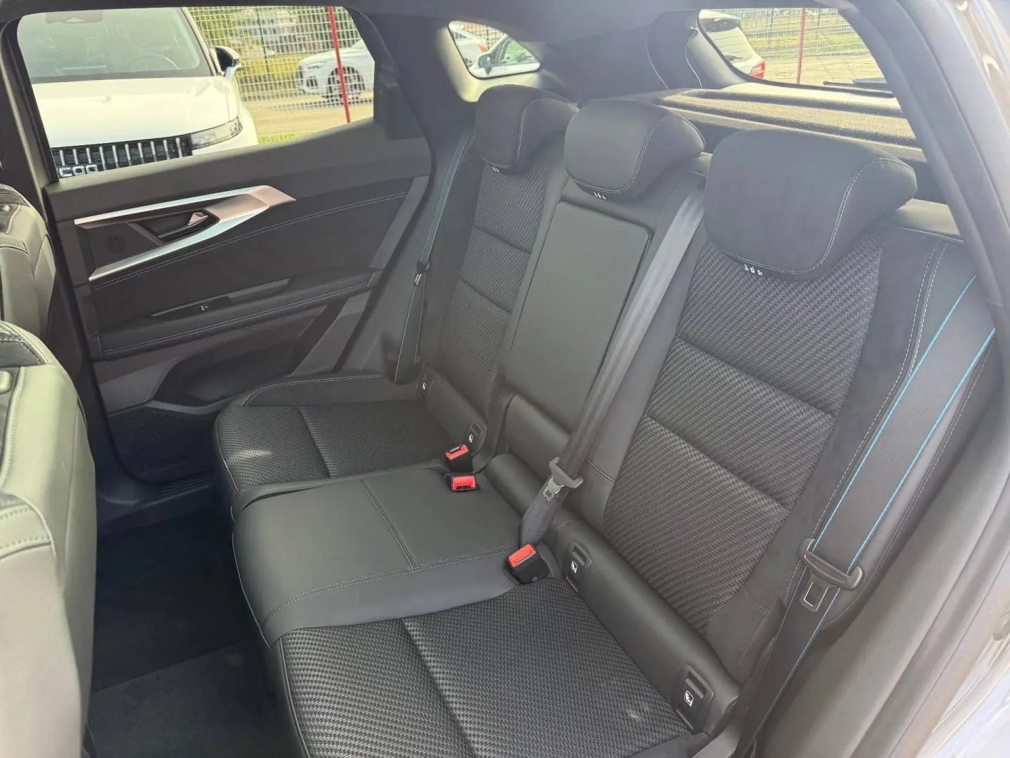 Vue latérale droite des sièges arrière en tissu carbone et Alcantara noir avec surpiqûres bleues du Renault Austral 2026.