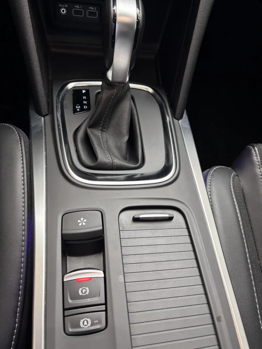 Gros plan sur la console centrale noire avec levier de vitesse automatique et commandes électroniques d'une Renault Mégane bleu 2023.