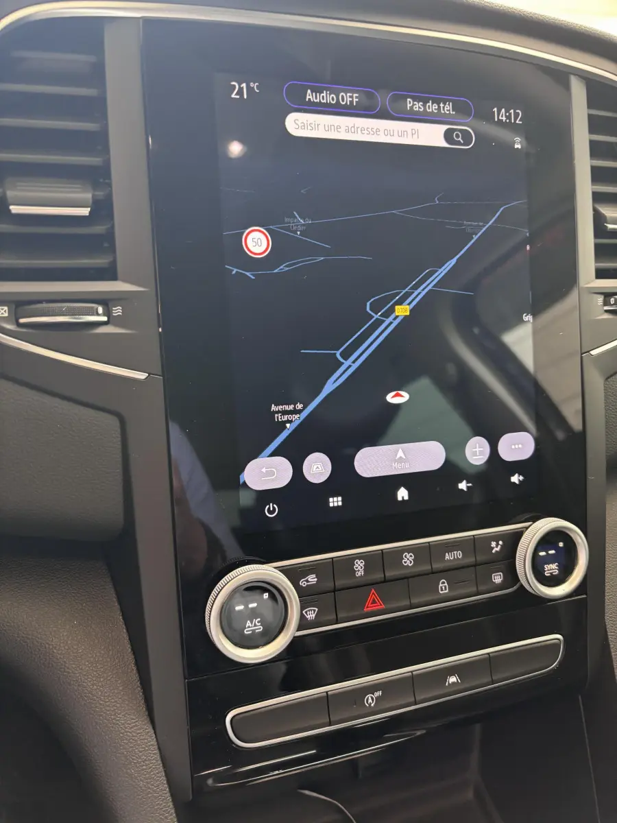 Vue rapprochée du tableau de bord central tactile de la Renault Mégane bleu 2023 avec commandes climatisation et navigation affichées