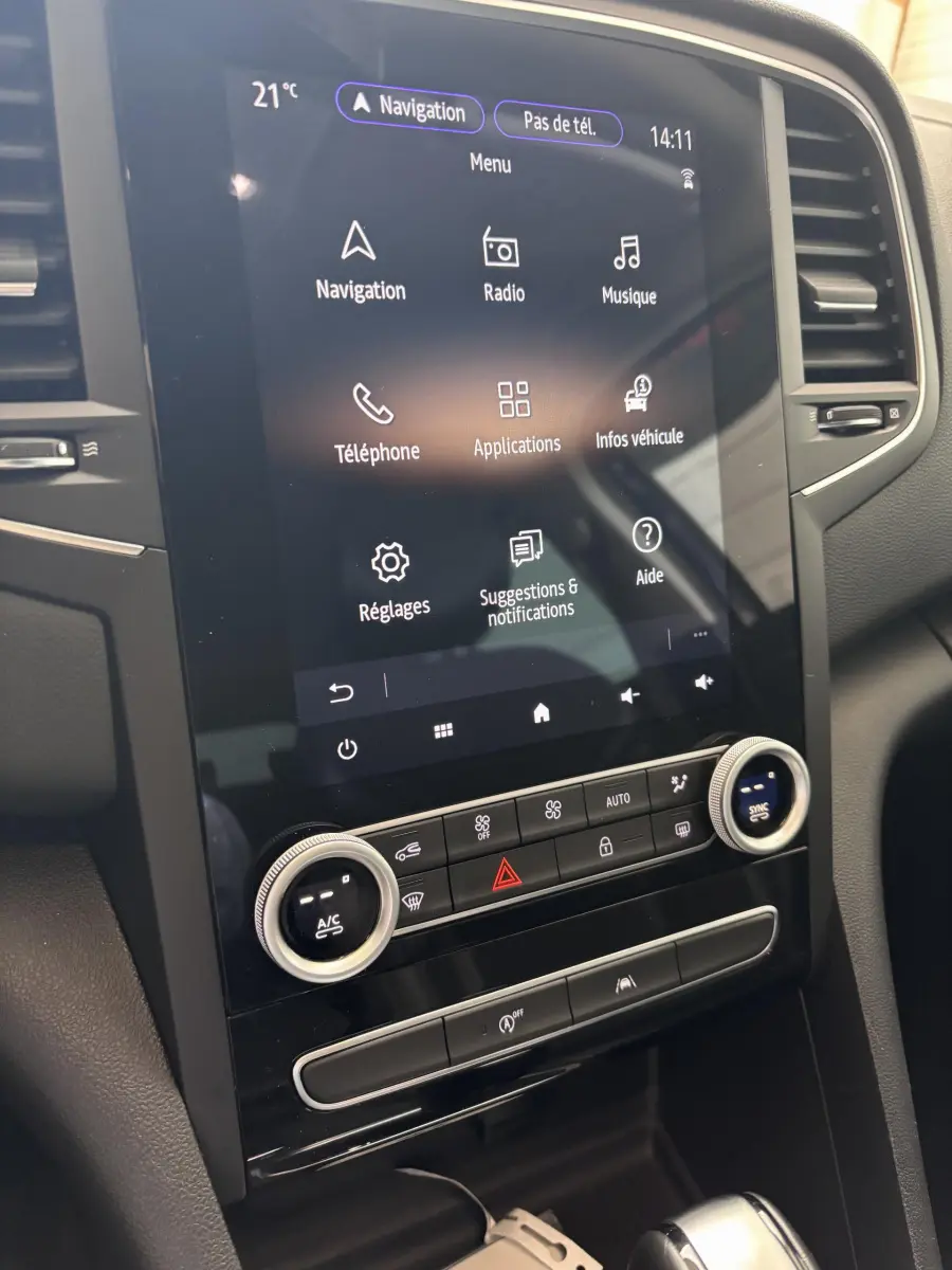 Vue rapprochée de l’écran tactile central et commandes de climatisation du tableau de bord de la Renault Mégane bleu 2023.